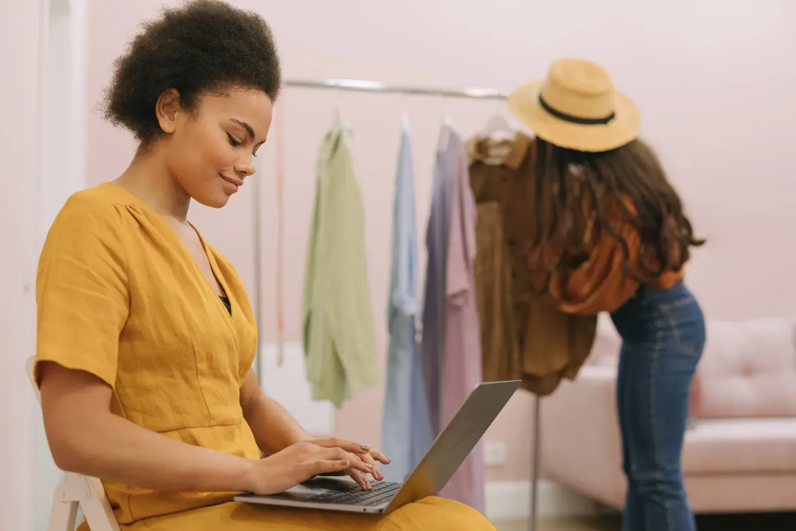 A boutique owner working on her laptop between clothing rails
